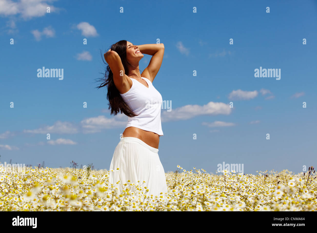 Giovane donna in bianco in piedi tra chamomiles in una giornata di sole Foto Stock