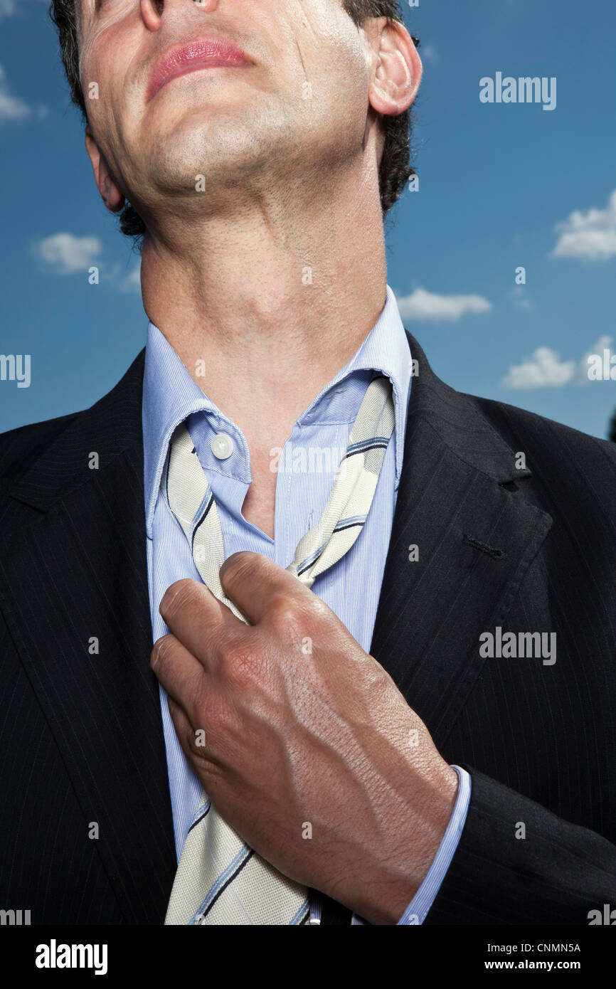 Imprenditore allentando la cravatta all'aperto Foto Stock