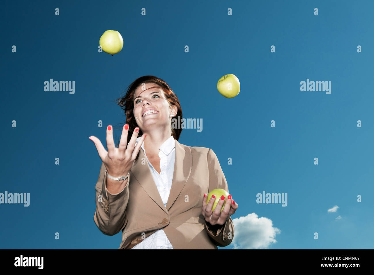 Imprenditrice juggling mele all'aperto Foto Stock