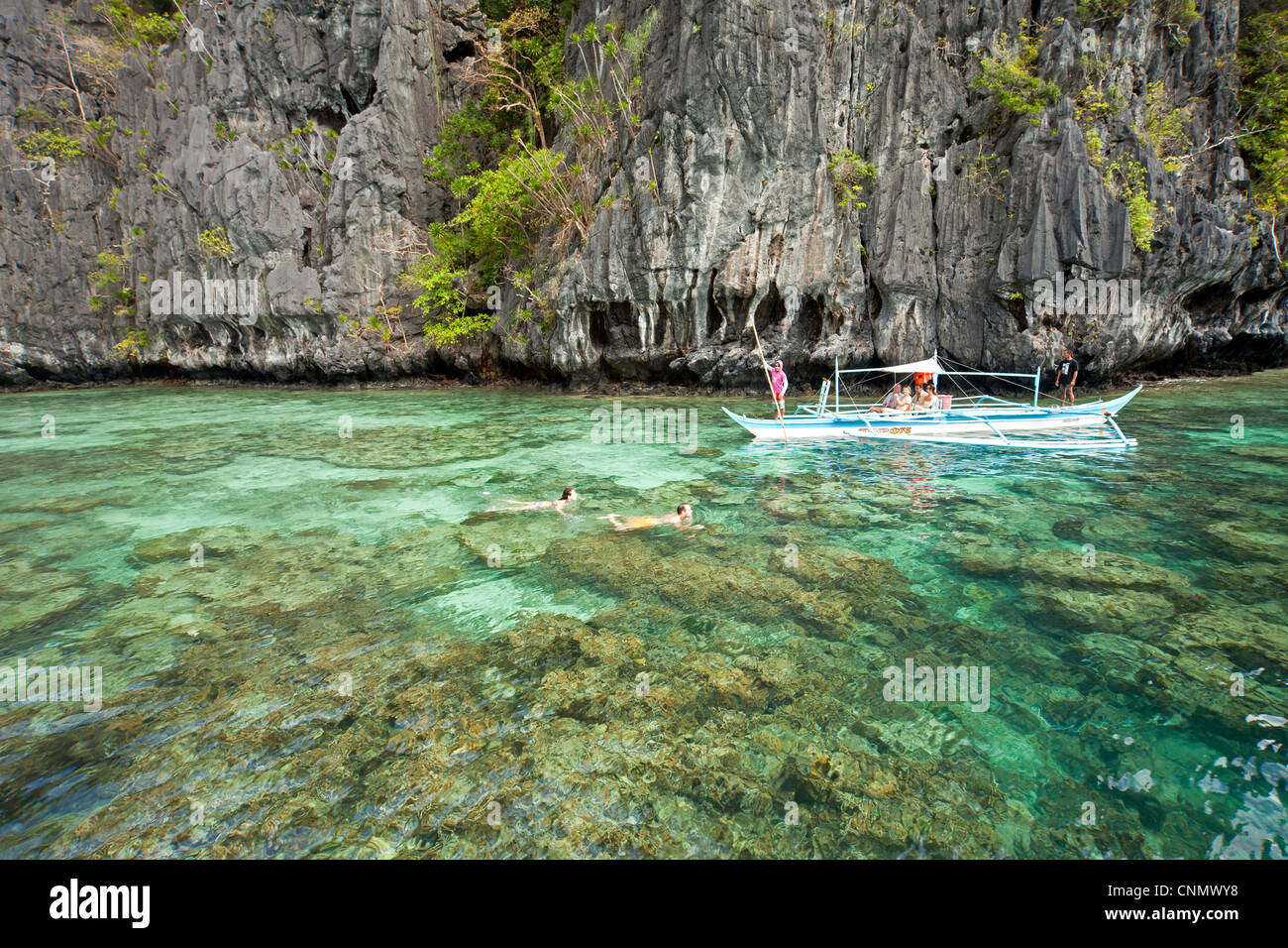 Tipica imbarcazione outrigger e turisti snorkeling presso la piccola laguna di Miniloc Island, El Nido, PALAWAN FILIPPINE, Asia Foto Stock