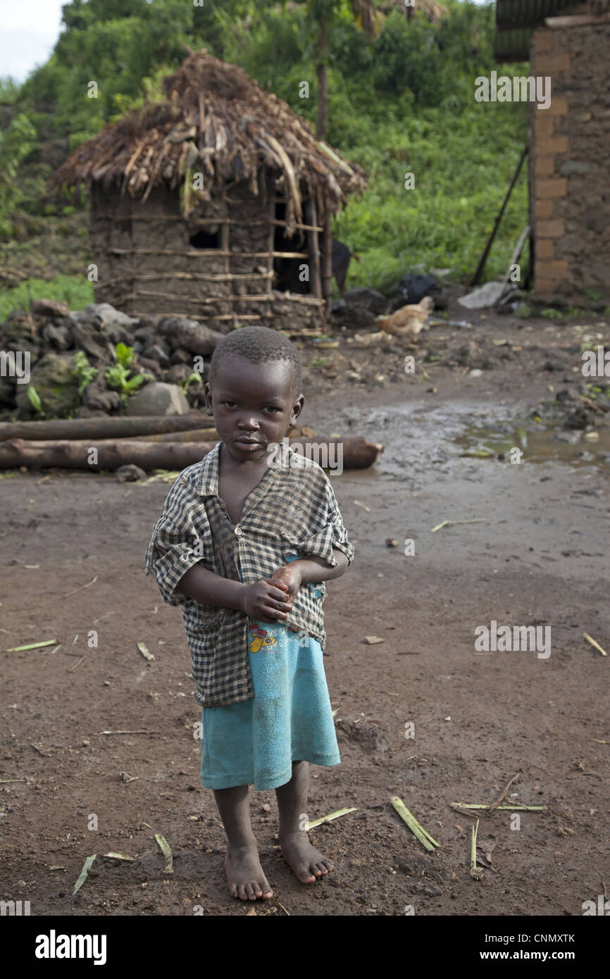 Bambino pigmeo, in piedi nel villaggio, montagne Virunga, Uganda Foto Stock