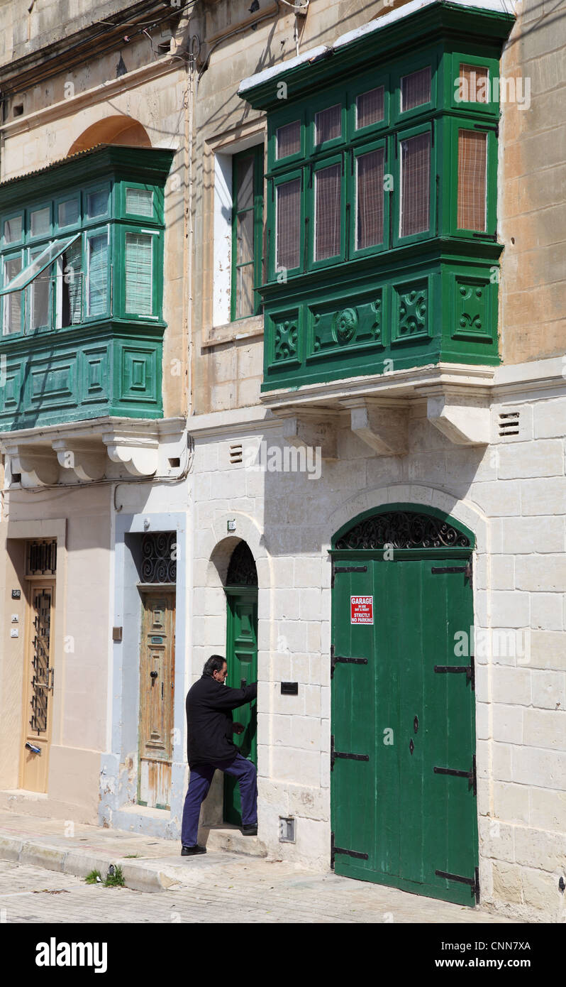 Il Maltese uomo entrando nella porta della casa tradizionale Rabat, Malta, Europa Foto Stock
