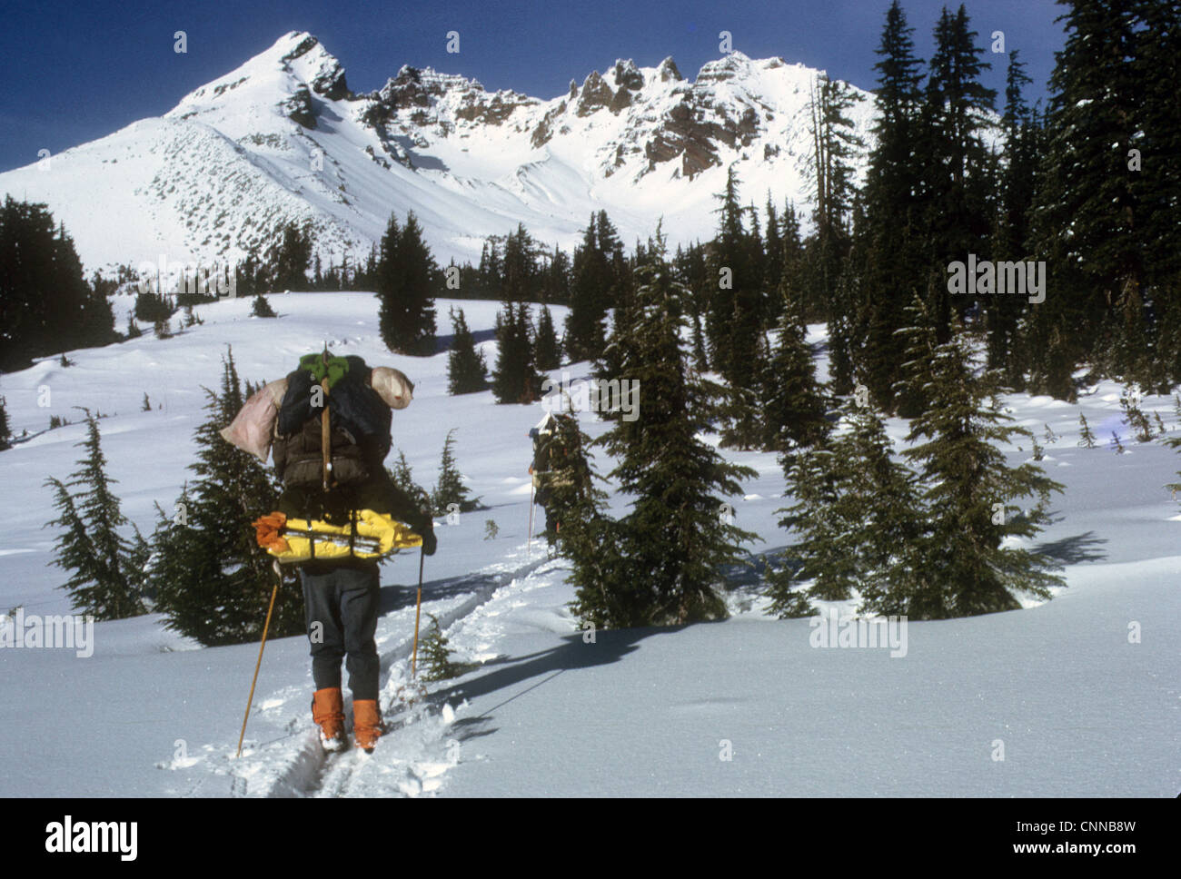 Donna sugli sci portano pesanti pack, Rotta in alto, 3 Suore deserto, Cascade Mountain Range, Oregon Foto Stock