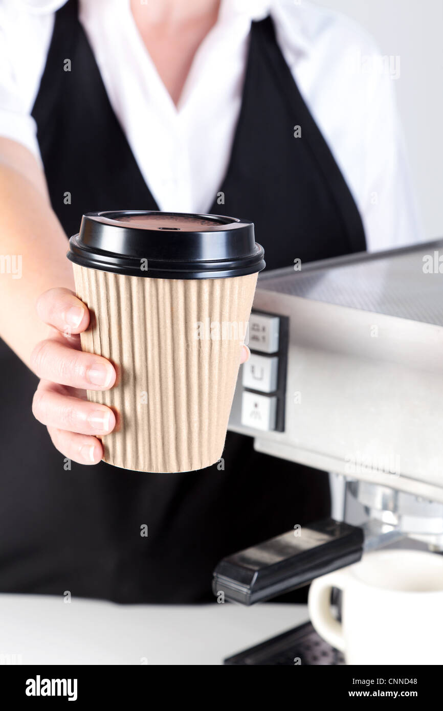 Foto di un barista consegna è un caffè in una carta monouso tazza da asporto. Foto Stock