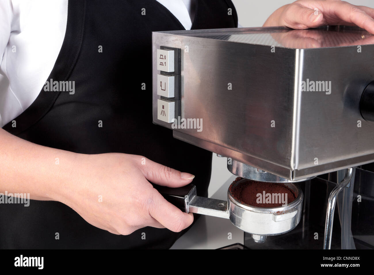 Foto di un barista mettendo un porta-filtro pieno di caffè appena macinato in una macchina per caffè espresso. Foto Stock