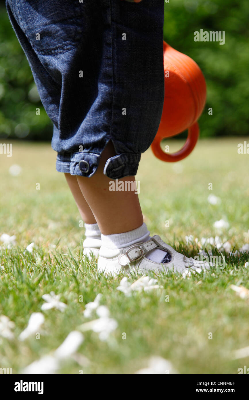 Gambe e piedi di bambina in piedi su erba in giardino, Farnham, Inghilterra Foto Stock