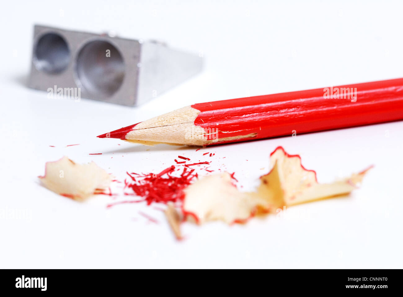 Red matite colorate e temperino su sfondo bianco. Foto Stock