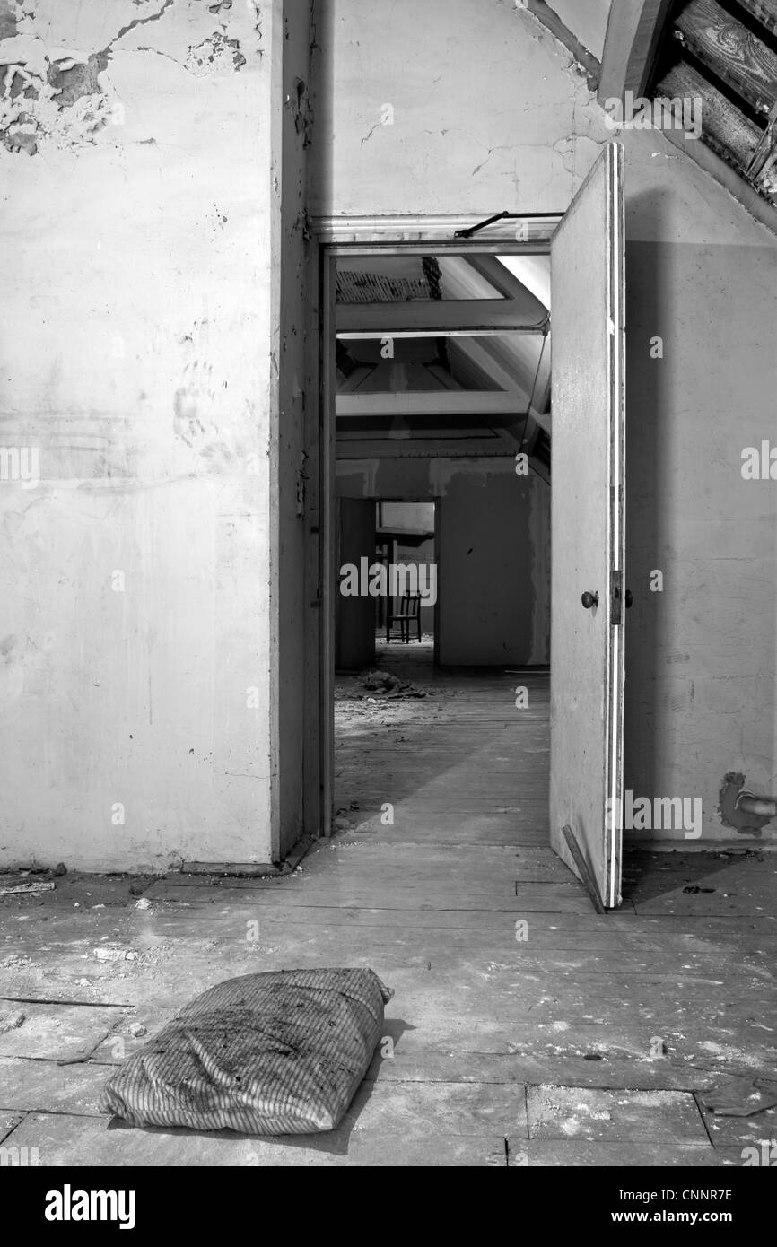 Una vecchia camera abbandonati attraverso una camera attraverso una camera. Eventualmente utilizzate da occupanti abusivi. Foto Stock