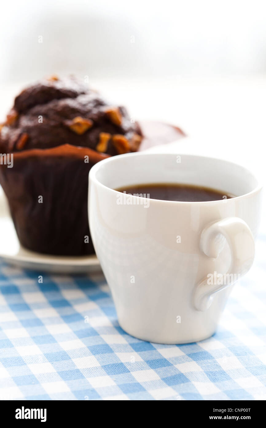 Close-up di una tazza di caffè nero e un muffin al cioccolato. Foto Stock