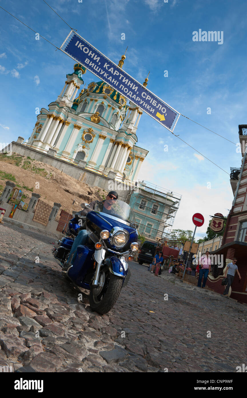 Un motore ciclista scende Andriyivskyy discesa nella parte anteriore del St Andrews Chiesa, Kiev, Ucraina, l'Europa. Foto Stock