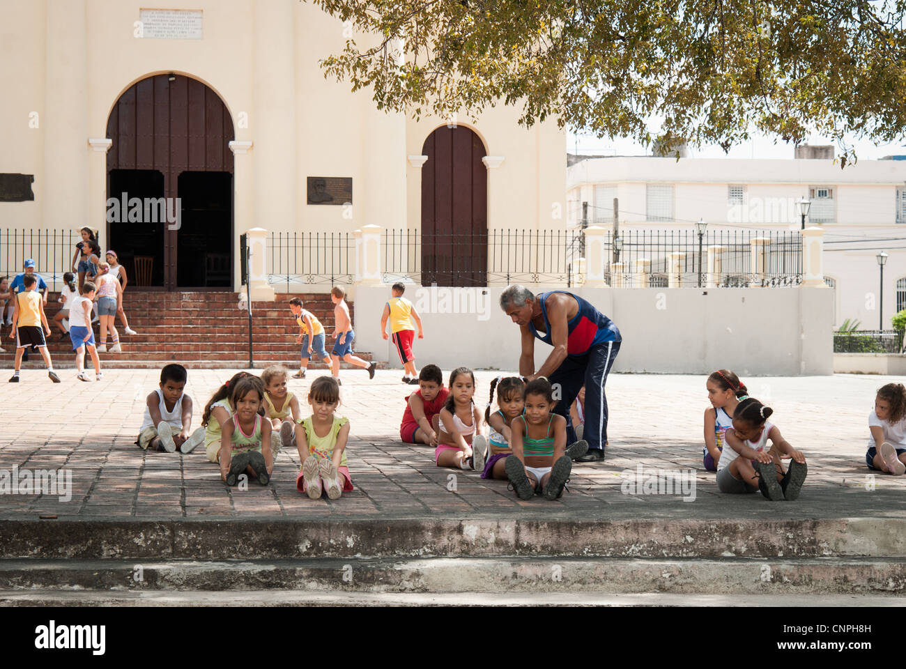 Ragazze cubane durante la loro lezione di PE al di fuori di una chiesa a Santa Clara. Ale ragazzi che giocano a calcio in background Foto Stock