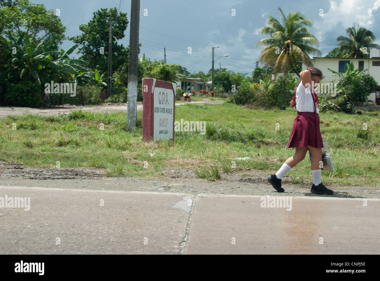 La scuola primaria ragazza andare a scuola a piedi, guardando nella telecamera Foto Stock