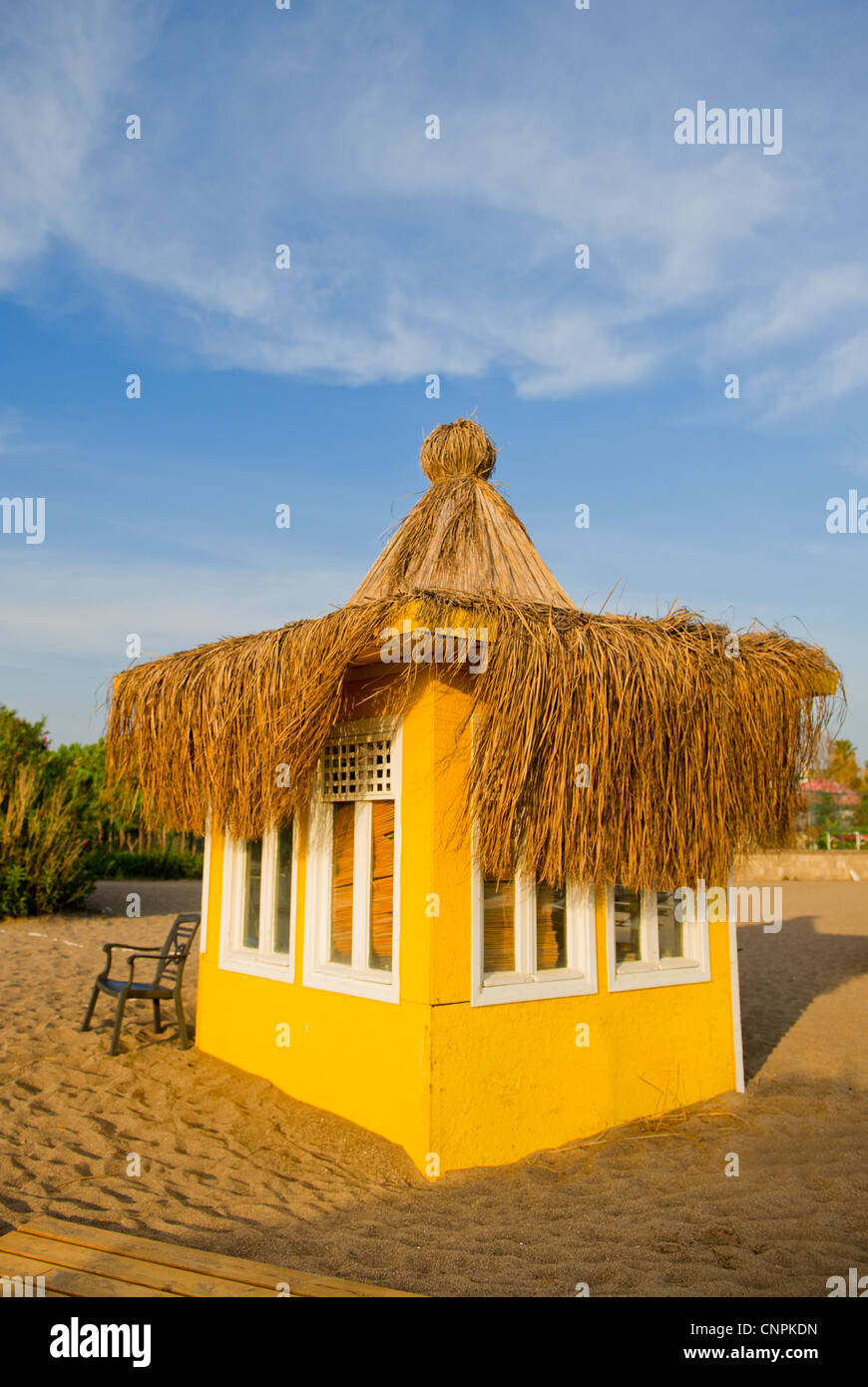 Giallo beach hut con tetto di paglia e sedia vuota Foto Stock