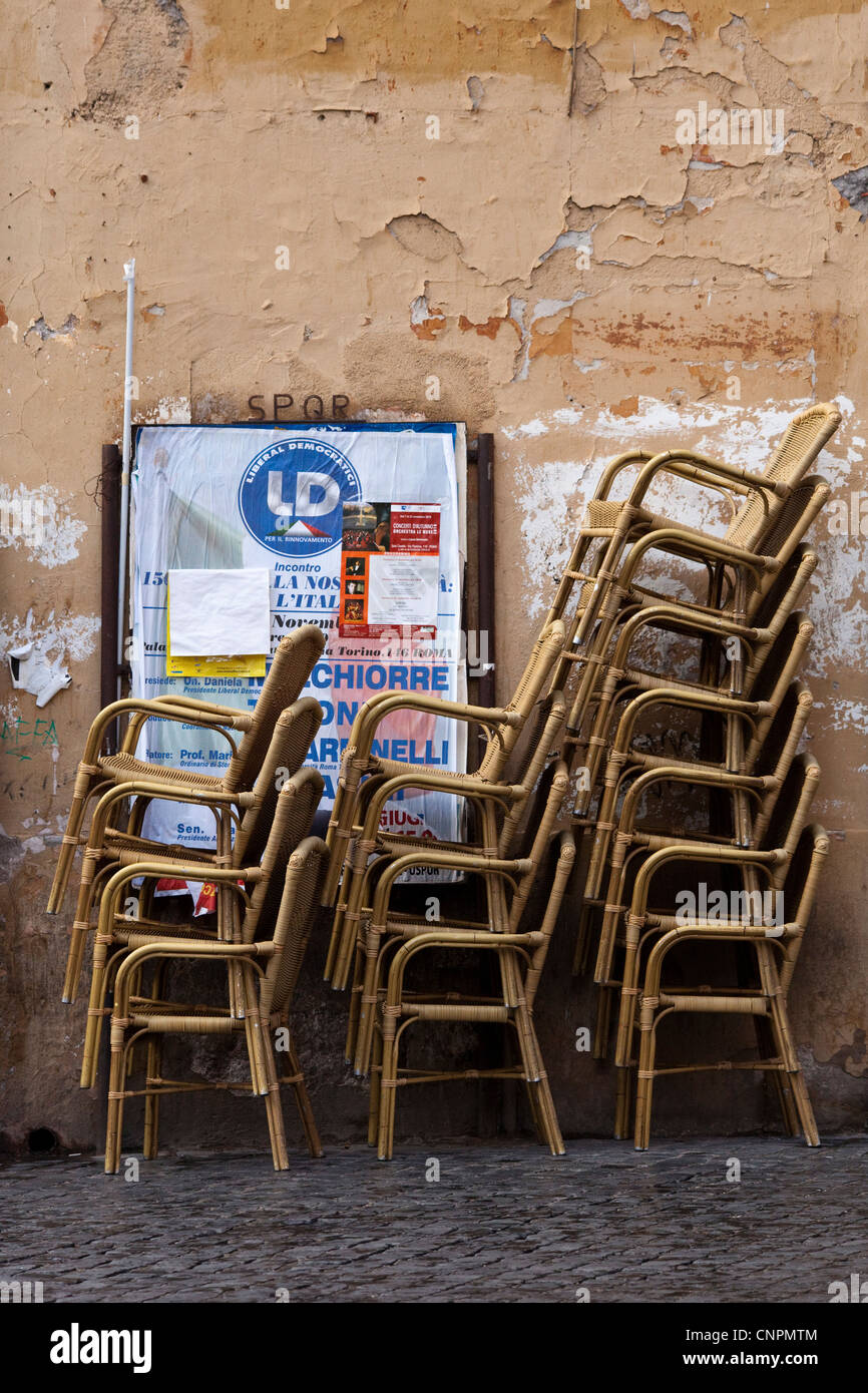 Cafe di vimini sedie impilate contro una parete con peeling la vernice e la locandina Foto Stock