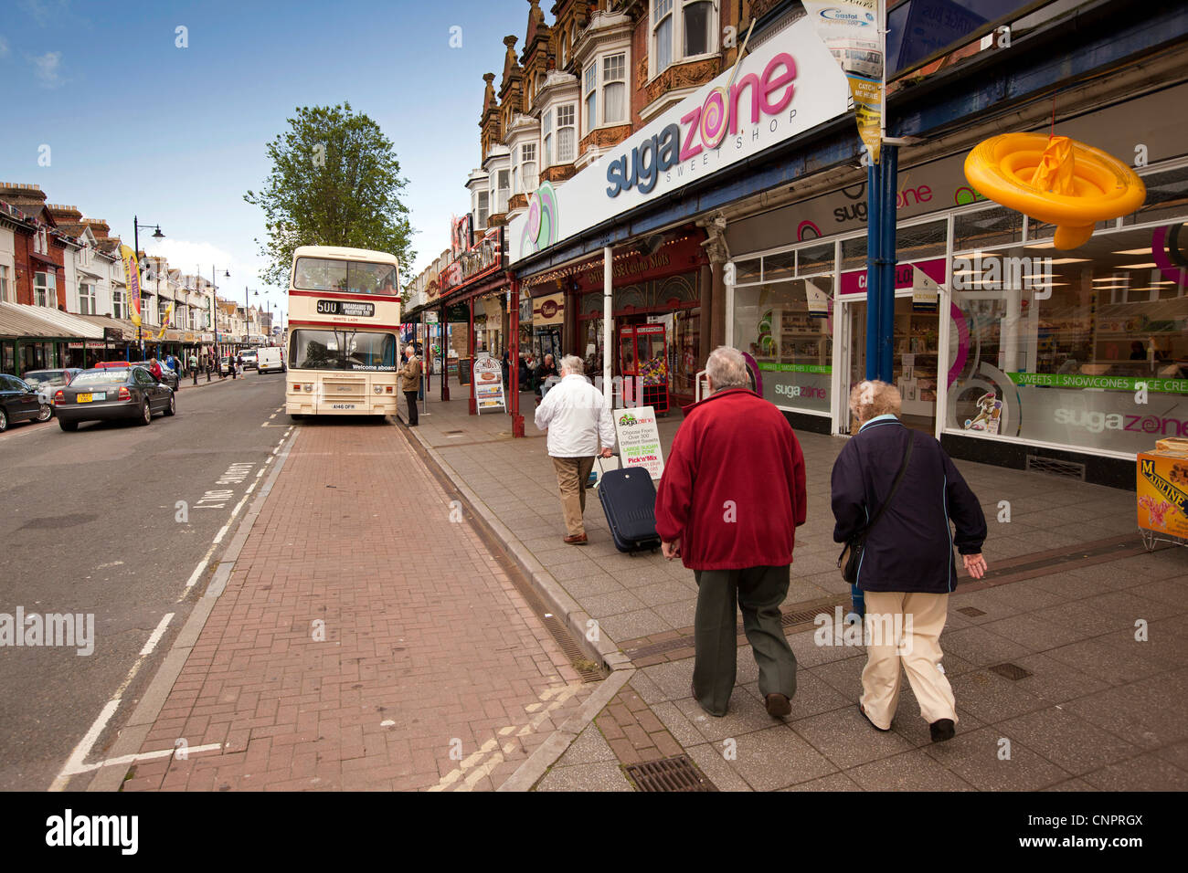 Regno Unito, Inghilterra, Devon, Paignton, Torbay Road, i visitatori a piedi con i bagagli alla fermata del bus Foto Stock