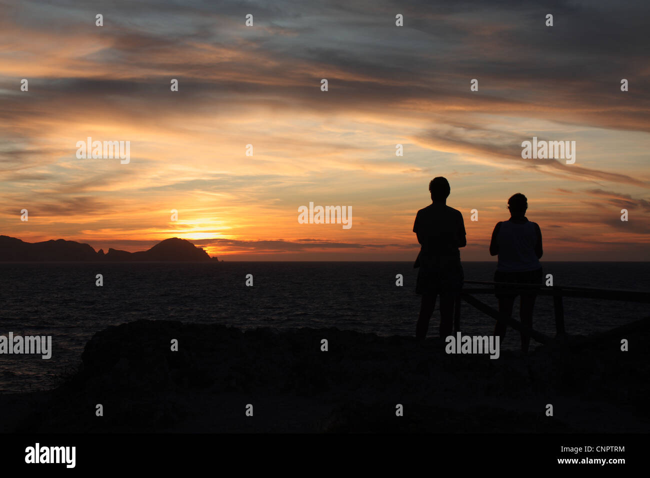 Un tramonto colorato a Palmarola sull isola di Ponza con due sagome umane in primo piano che guarda al mare. Foto Stock