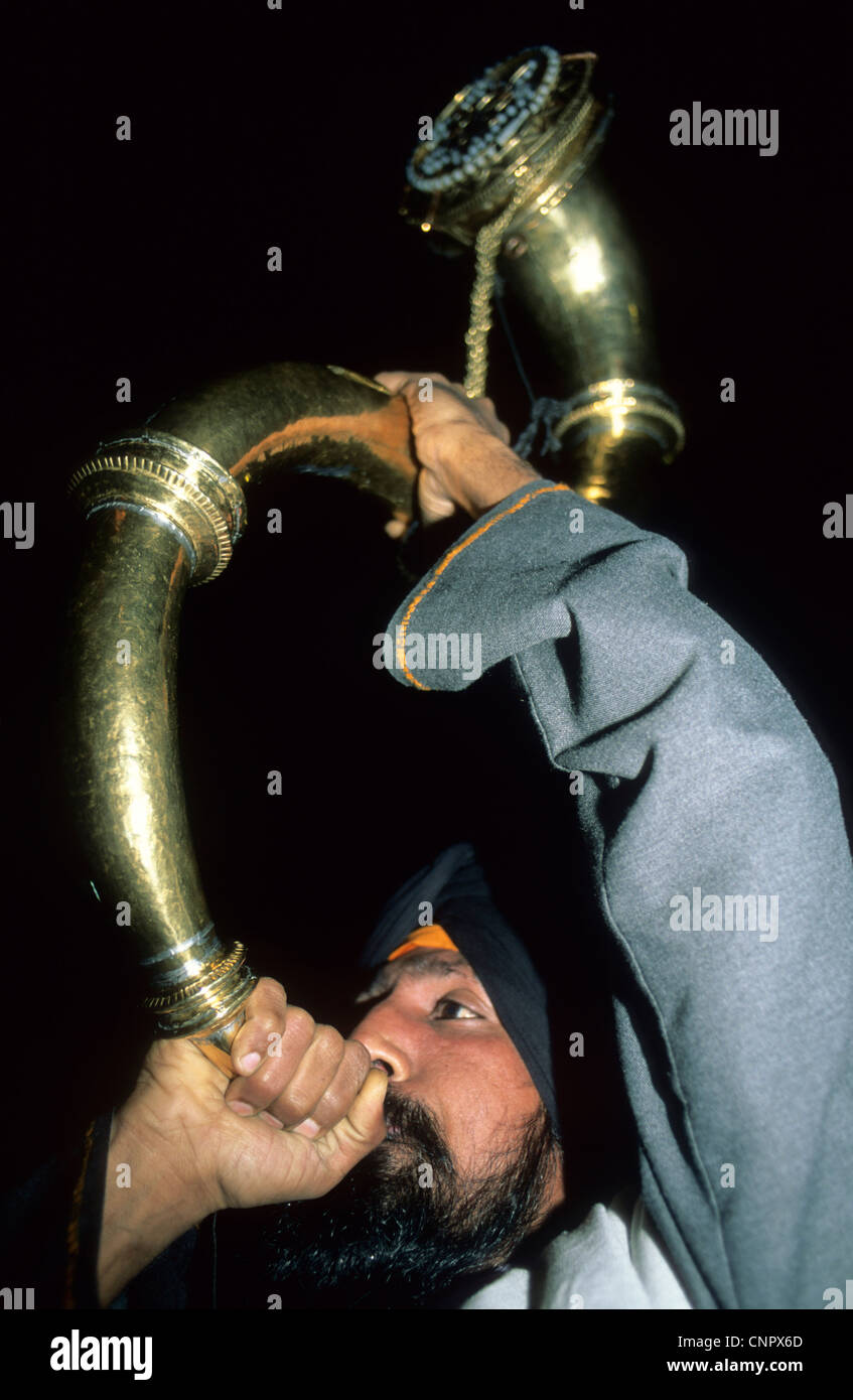 La religione sikh uomo soffiando il clacson al Tempio d'oro di Amritsar, India. Principale Luogo di culto per coloro che professano la religione Sikh. Foto Stock