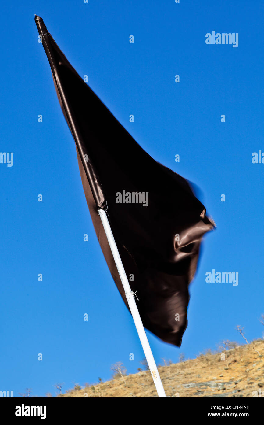 Diagonal shot, ritratto, verticale di una pianura setosa bandiera nera agitando in una brezza leggera Foto Stock