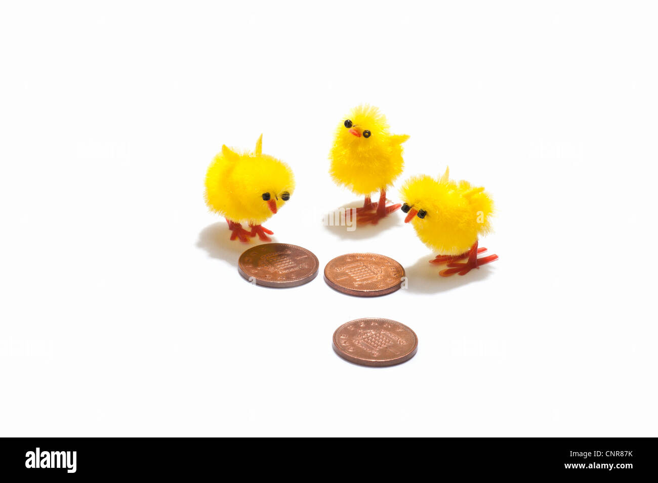 Tre pulcino di Pasqua decorazioni guardando penny monete Foto Stock