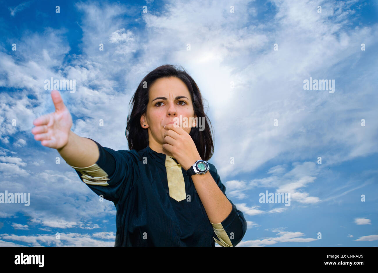 Donna soffiando fischio contro il cielo blu Foto Stock