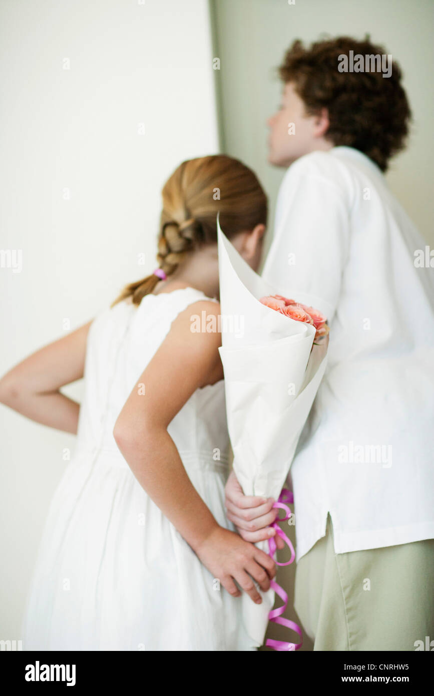 I giovani fratelli holding bouqet di fiori dietro il dorso, spiata attraverso la porta Foto Stock