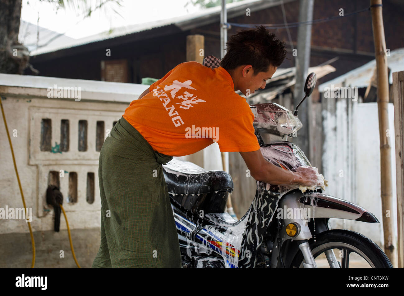 L'uomo il lavaggio moto a Mandalay, Myanmar Foto Stock