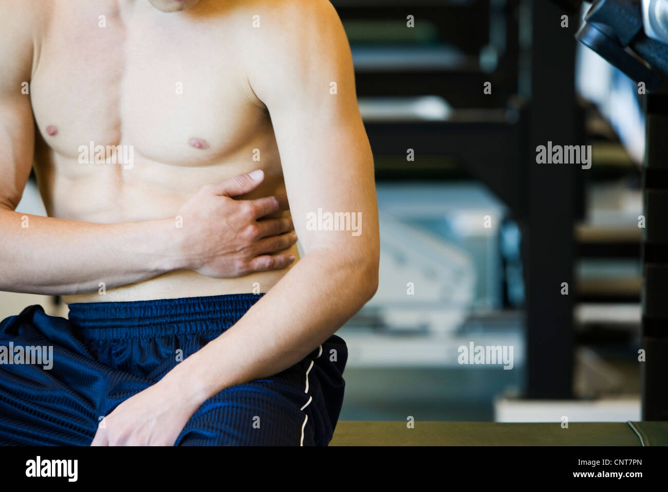 Uomo Barechested toccando l'addome, metà sezione Foto Stock