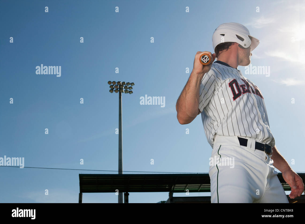 Giocatore di baseball azienda bat, guardando sopra la spalla Foto Stock