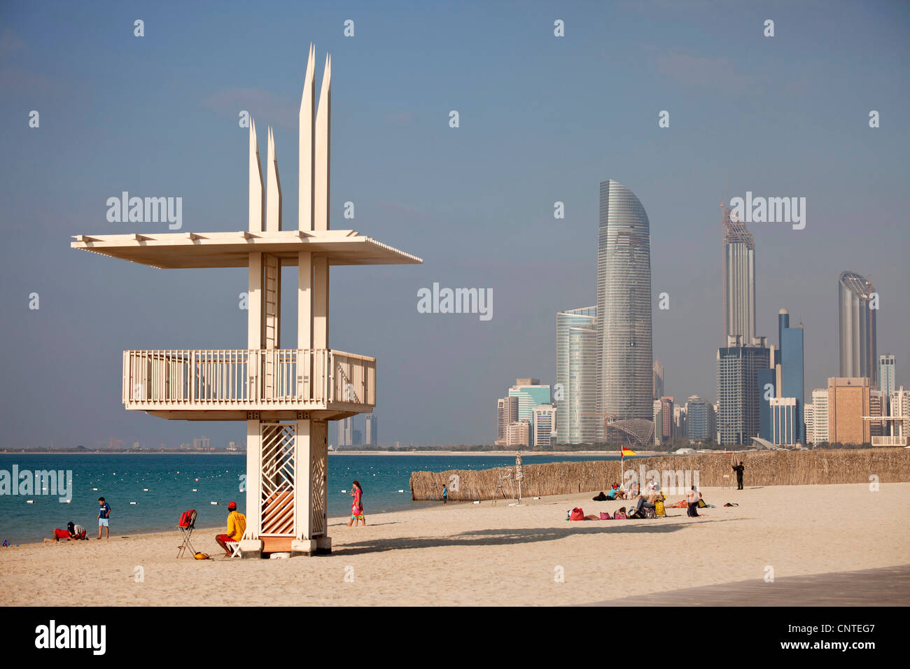 La spiaggia pubblica con bagnino edificio e lo skyline di Abu Dhabi, Emirati Arabi Uniti, Asia Foto Stock