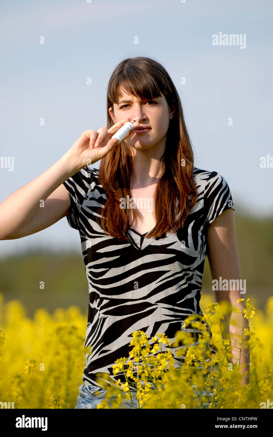 Giovane donna in una rapefield con spray nasale, Germania Foto Stock