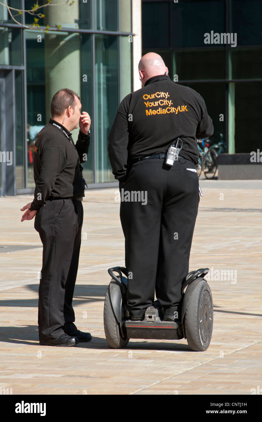 Due guardie di sicurezza, uno su un Segway a MediaCityUK, Salford Quays, Manchester, Inghilterra, Regno Unito Foto Stock