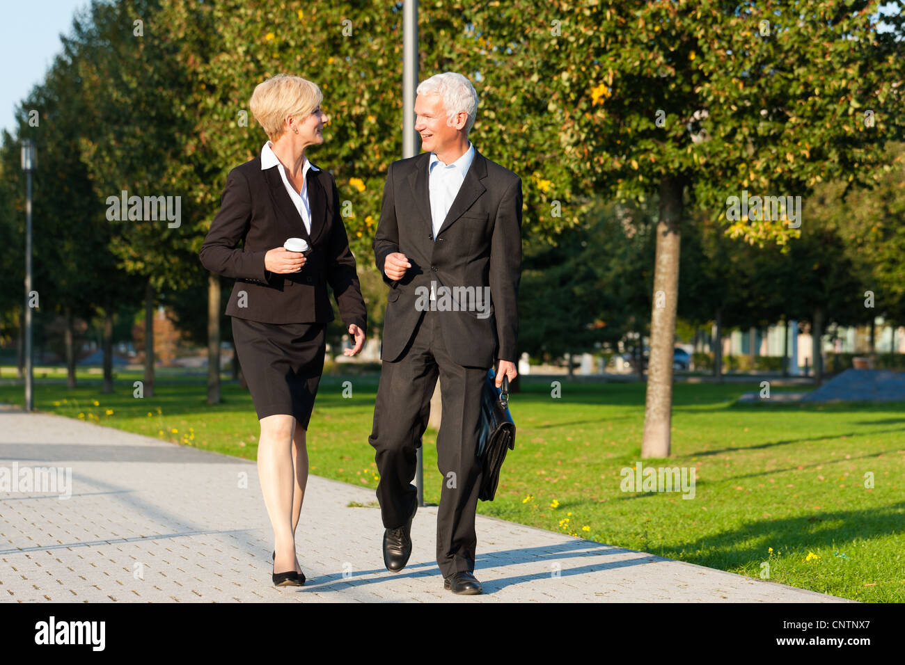 La gente di affari - maturo o senior - parlando all'aperto e camminare in un parco Foto Stock