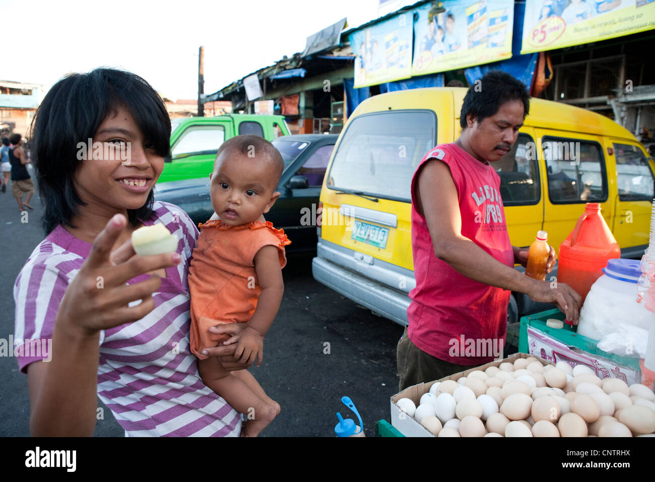 Donna con il suo bambino sta acquistando Balut, un anatra fecondate di embrioni da un fornitore sul ciglio della strada. Mercato del carbonio, Cebu City, Filippine Foto Stock