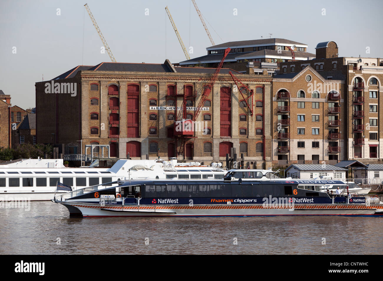 Il re Enrico banchine a Wapping mostra red gru sul magazzino e Thames Clipper in primo piano. Foto Stock