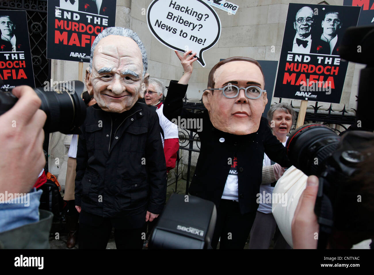 I manifestanti che indossano maschere di James Murdoch (L) e suo padre Rupert (R) dimostrano al di fuori dell'inchiesta Leveson Alta Corte Foto Stock