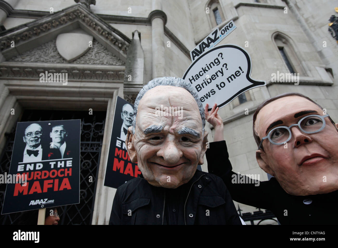 I manifestanti che indossano maschere di James Murdoch (L) e suo padre Rupert (R) dimostrano al di fuori dell'inchiesta Leveson Alta Corte Foto Stock