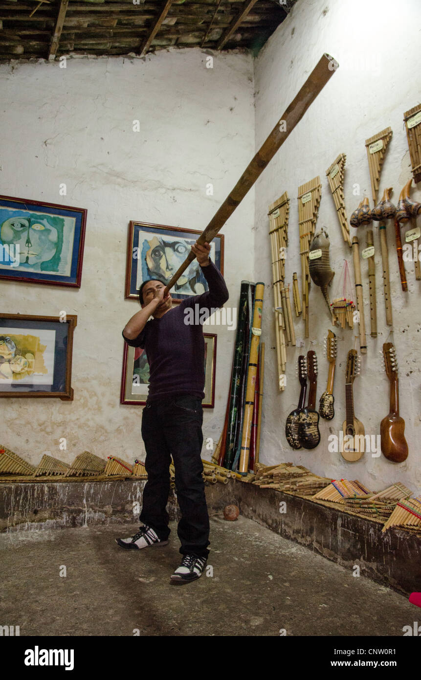 L'uomo la riproduzione di musica tradizionale strumento al mercato di Otavalo Ecuador Foto Stock