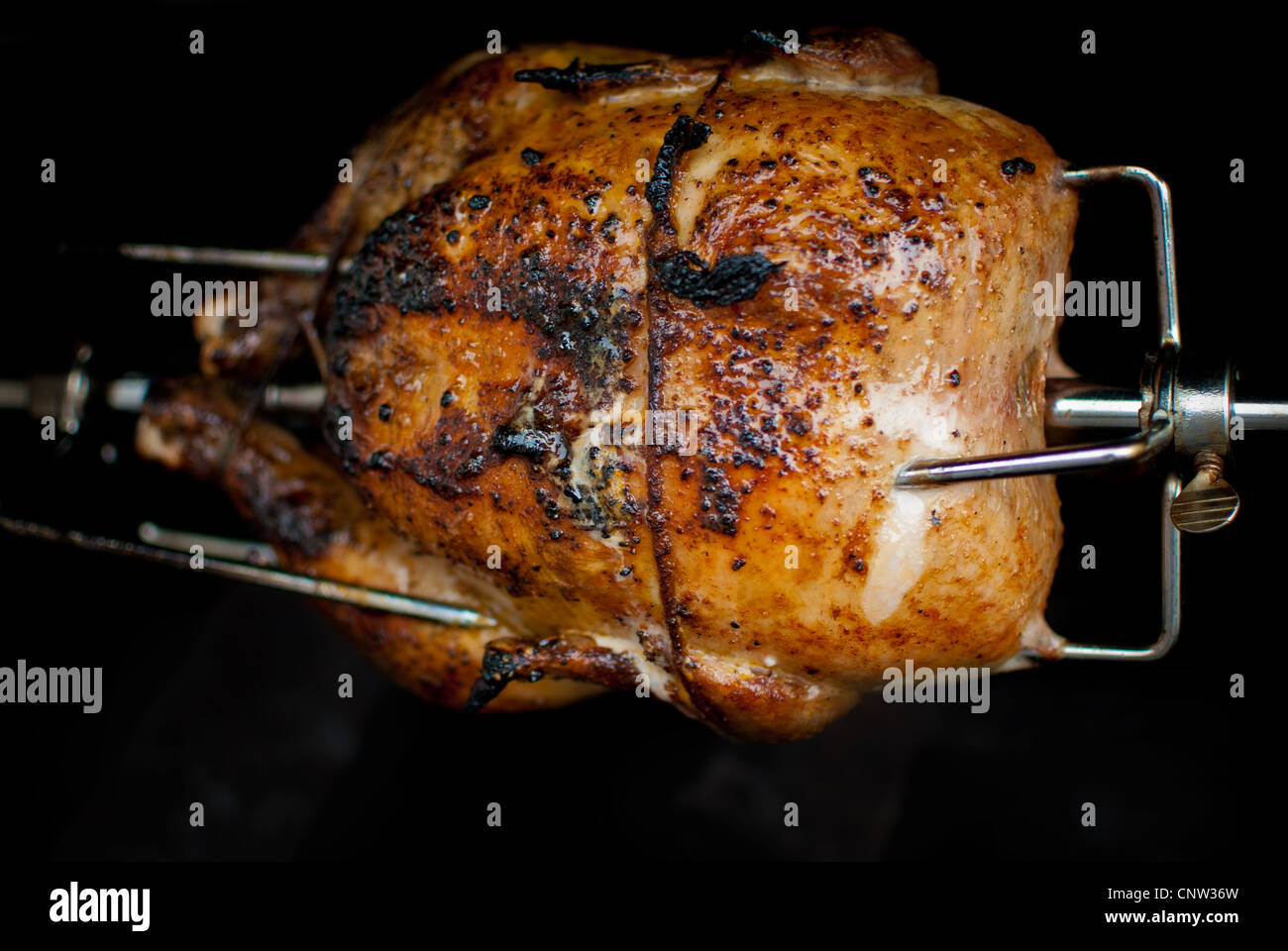 Grigliare il pollo su un girarrosto spiedo su un grill. Foto Stock