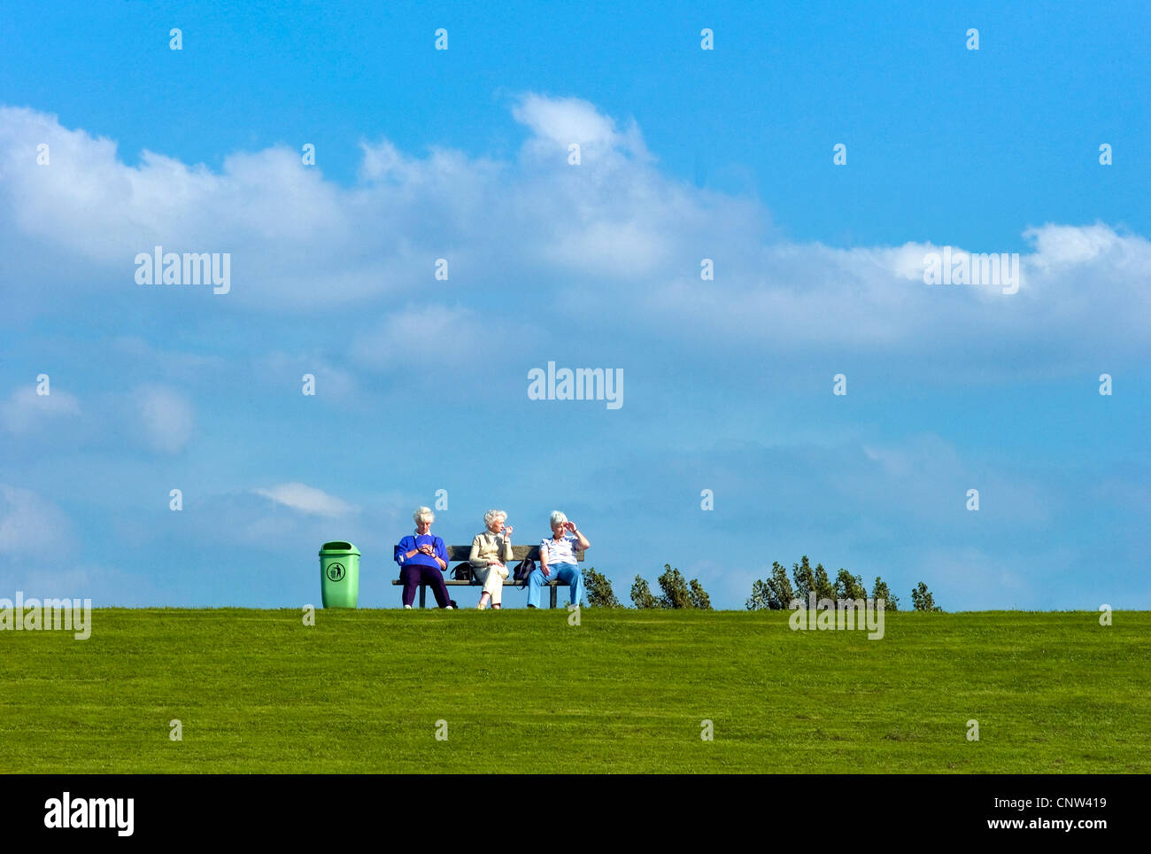 Tre bianchi dai capelli donna seduta su una panchina su una diga del Mare del Nord in Dorum-Neufeld, Germania, Bassa Sassonia Foto Stock