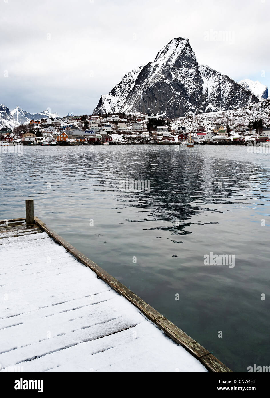 Villaggio di Reine con montagne coperte di neve di Olstind in distanza, Isole Lofoten in Norvegia Foto Stock