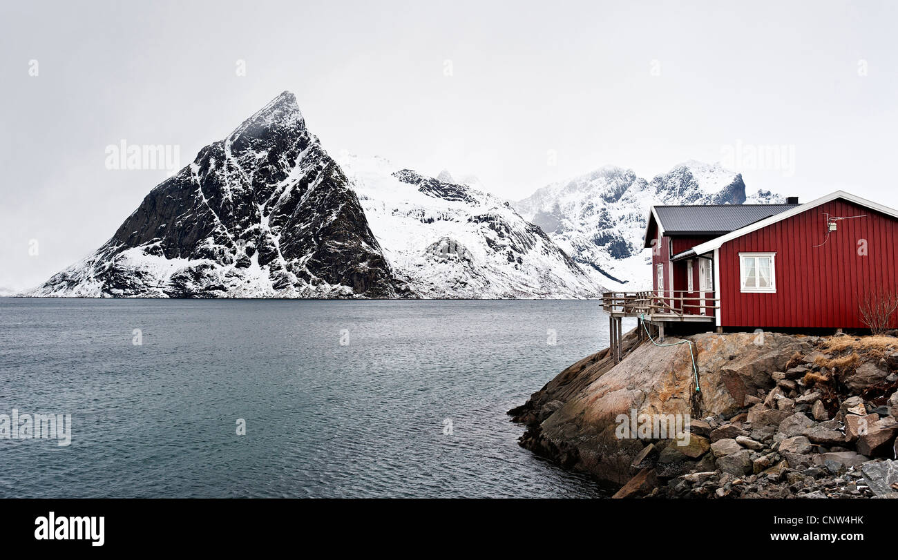 Un rorbu o dei pescatori del rifugio sulla costa vicino a Hamnoy, con Olstind mountain n lo sfondo Foto Stock
