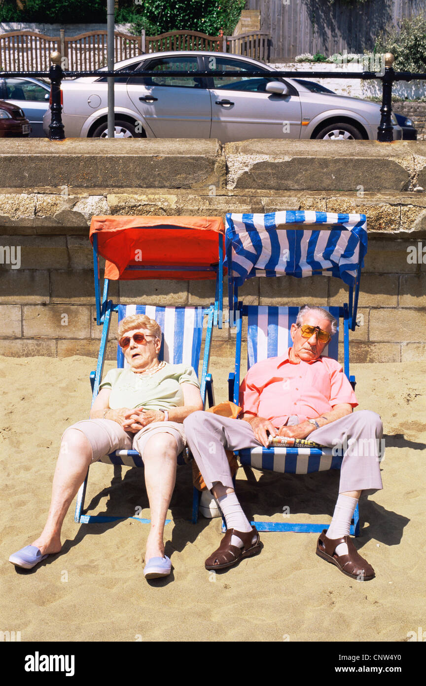 Gran Bretagna, Inghilterra, Hampshire, Isle of Wight, Sandown, coppia di anziani dormire in sedie a sdraio sulla spiaggia di Sandown Foto Stock