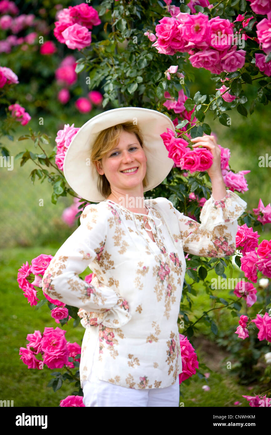 Rose ornamentali (Rosa spec.), donna lo sniffing di rose, Germania Foto Stock