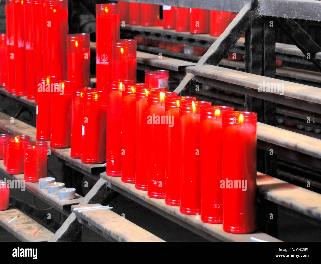 Un lrow di candele rosse di preghiera votiva nella Chiesa. Foto Stock