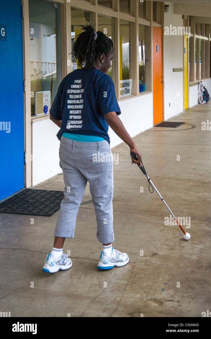 Usando un bastone bianco, un afro-americano di preteen girl trova il suo modo a bambini ciechi il Learning Center di Santa Ana CA. Foto Stock