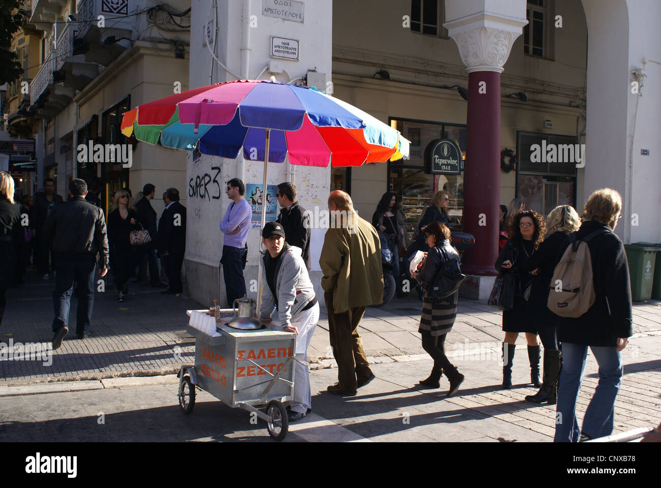 Pedoni passare una bevande calde venditore ambulante di attesa per i clienti di Salonicco, Grecia Foto Stock