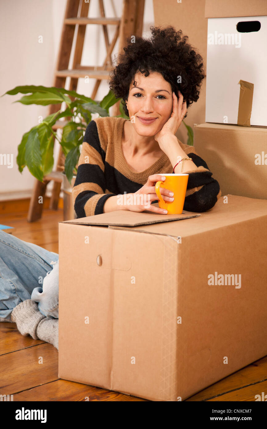 Un allegro donna prendendo una pausa caffè mentre casa in movimento Foto Stock