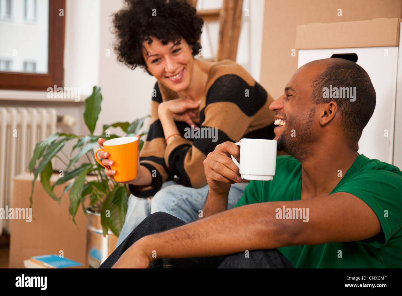 Una ridente giovane prendendo una pausa caffè mentre il trasloco, close-up Foto Stock