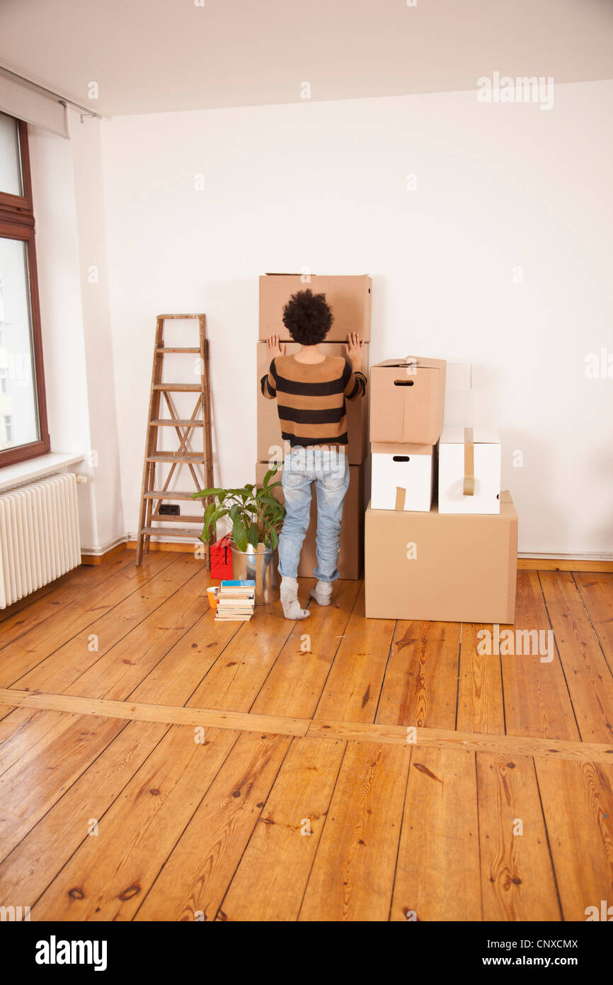 Una donna spingendo una scatola di movimentazione in posizione sulla sommità di una pila di scatole Foto Stock