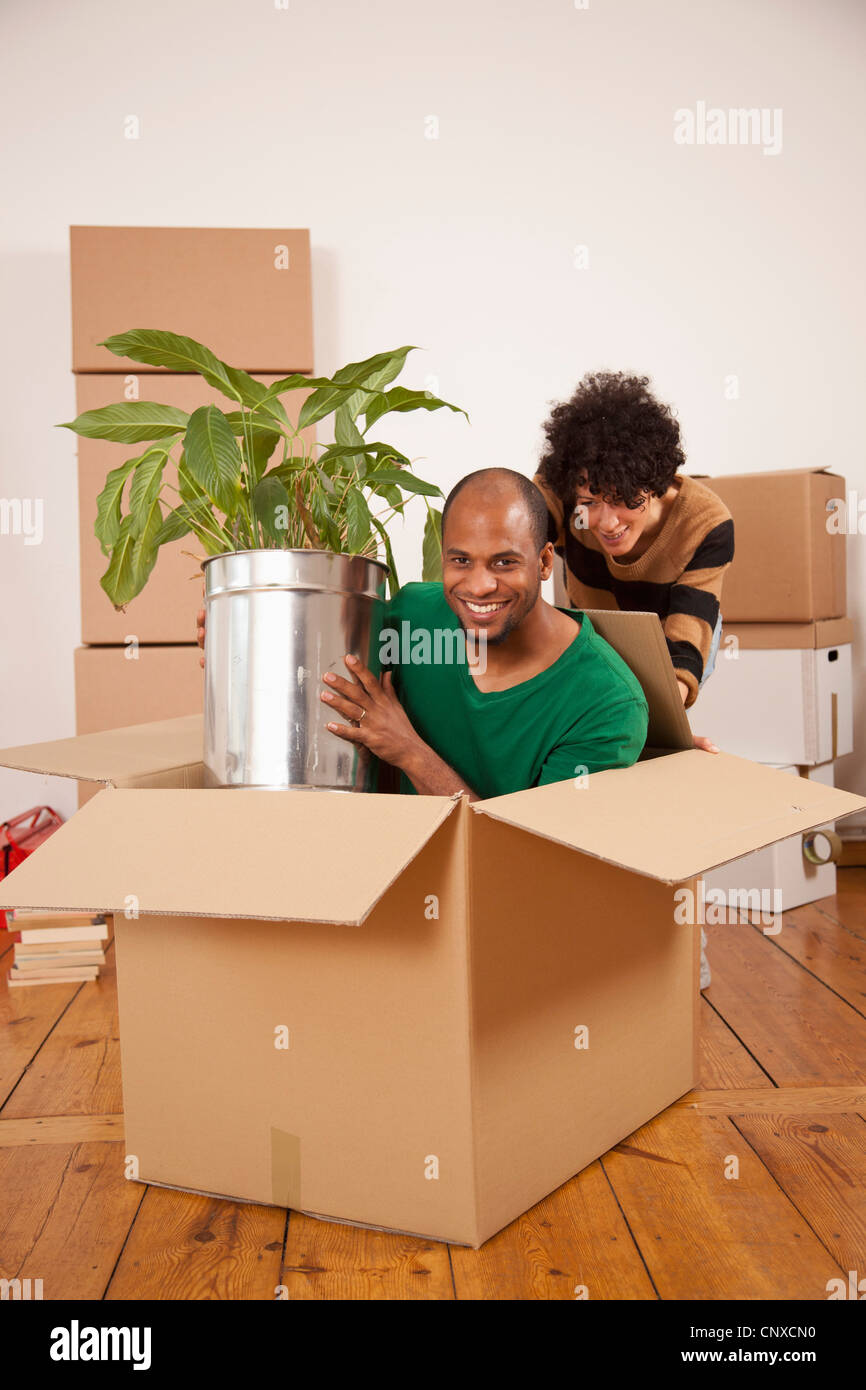 Una donna spingendo un uomo seduto all'interno di una scatola di movimentazione Foto Stock